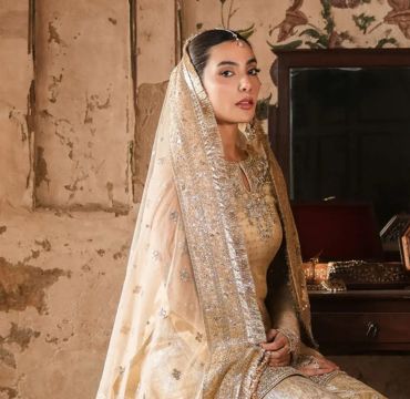 A colorful selection of Faiza Saqlain's festive dresses hangs in a boutique, offering variety and elegance for special occasions.